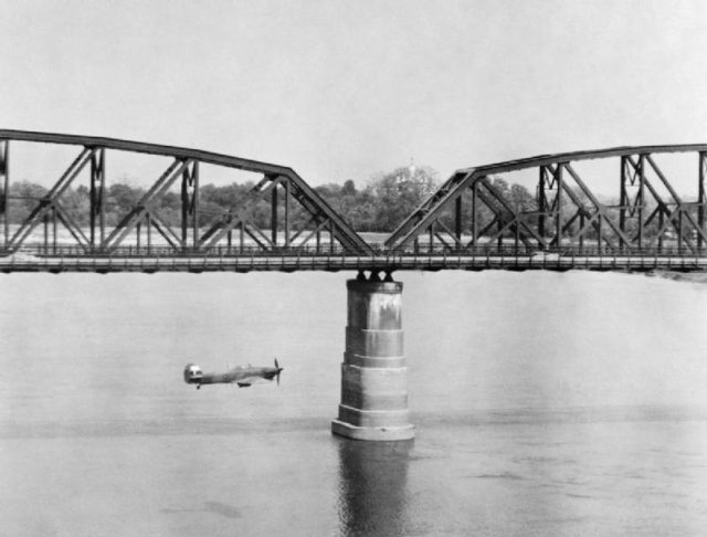 An RAF Hawker Hurricane Mk IIC flies alongside Aya Bridge, which spans the Irrawaddy River near Mandalay, Burma, during a low-level reconnaissance sortie, March 1945.