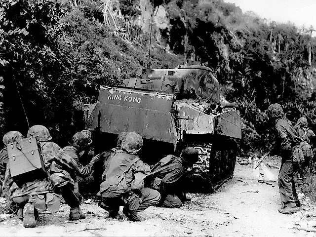 US Marines taking shelter behind an M4 Sherman tank on the northern end of Saipan on July 8, 1944