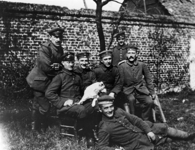 Hitler is seated on the far right of the group. By Bundesarchiv – CC BY-SA 3.0 de