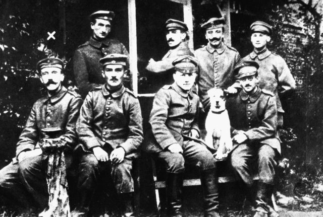 A young Hitler (farthest left at bottom row) posing with other German soldiers and their dog Fuchsl.
