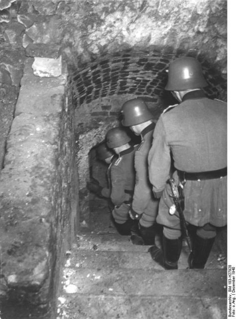 The German Order Police “Orpo” descending to the cellars on a “Jew-hunt,” Lublin, December 1940; Bundesarchiv – CC-BY SA 3.0