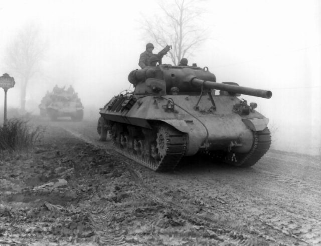 American tanks move through fog at the Bulge.
