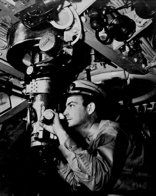 Officer at periscope in control room of submarine.