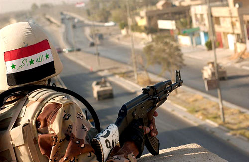 An Iraqi Soldier armed with an AK-47 stands guard