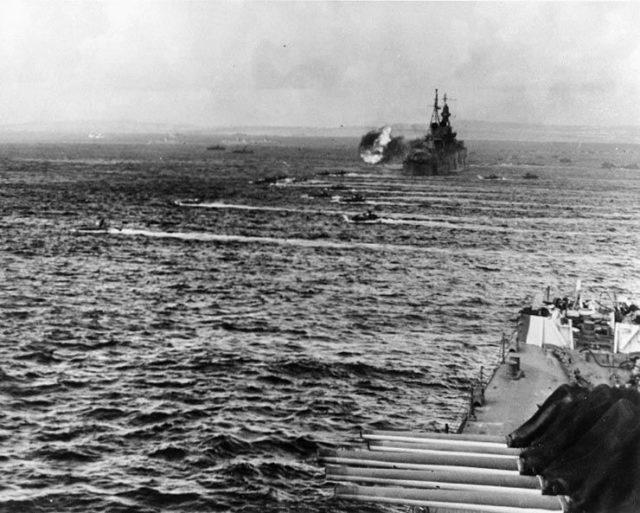LVTs going in at the battle of Saipan, 15 June 1944. Ship in foreground is USS Birmingham (CL-62); the cruiser firing in the distance is USS Indianapolis (CA-35).