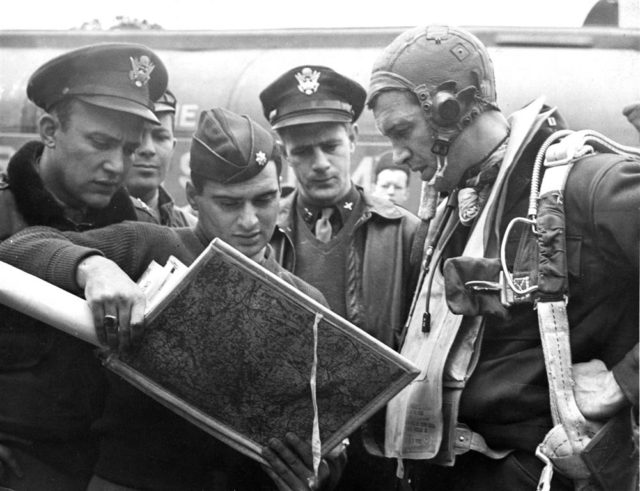 In full combat gear, Stewart looks at G-2 maps and photos of the target area before taking off for Germany.