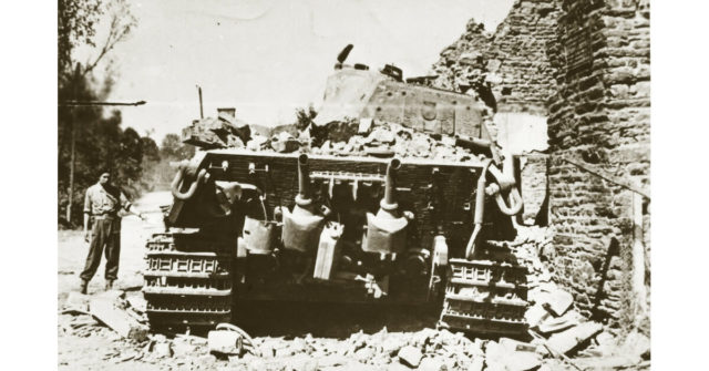 A rear view of the knocked out tank with a British soldier alongside looking suitably amazed.