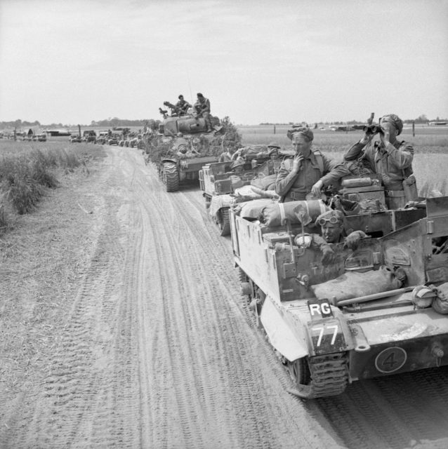 Carriers and a Sherman observation tank of an artillery headquarters unit moving up to cross the Orne river during Operation ‘Goodwood’, 18 July 1944.