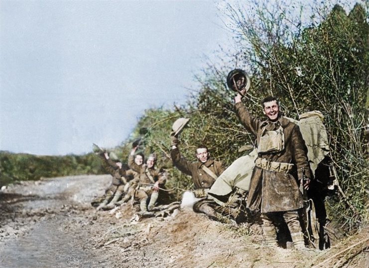 Soldiers in a field wave their helmets and cheer on Armistice Day, November 11, 1918. Photo colourised by Royston Leonard / mediadrumworld.com