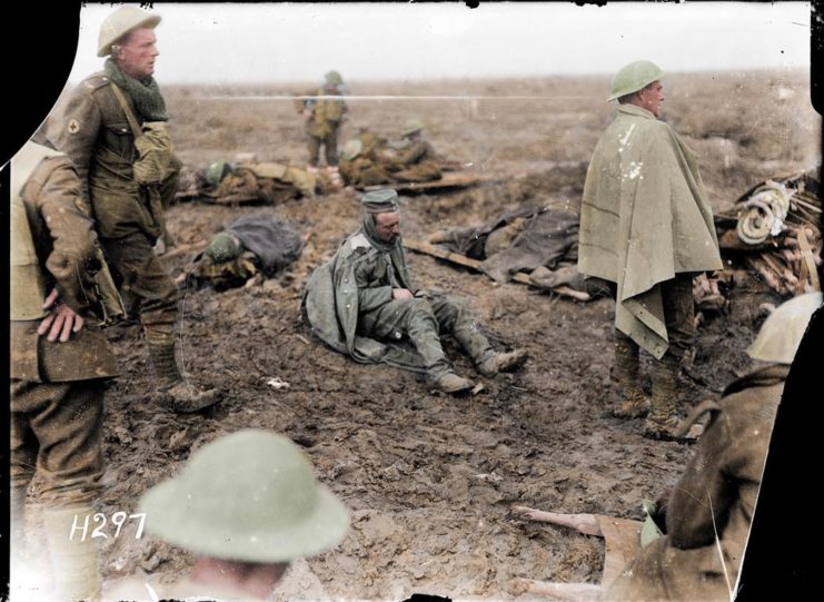 A badly wounded German prisoner sits on the ground awaiting medical treatment. Battle of the Somme. Photo colourised by Royston Leonard / mediadrumworld.com
