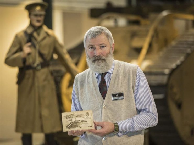 David Willey, curator of the Tank Museum in Bovington, Dorset, with the Christmas card sent by Elliot Hotblack (depicted behind) 100 years ago. Photo credits: The Tank Museum