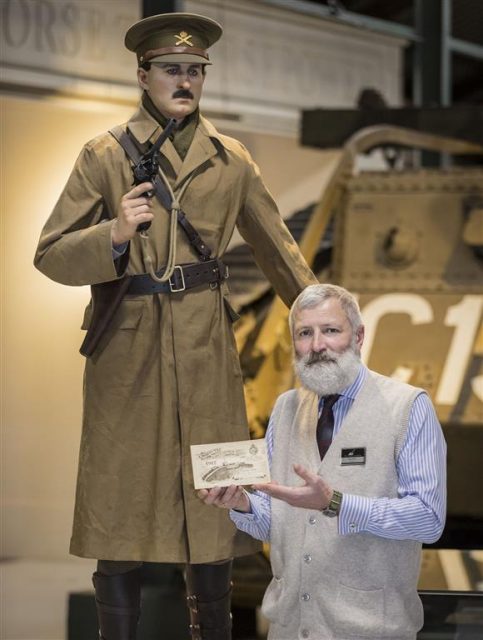 Tank Museum curator David Willey with a Christmas card sent by tank hero Elliot Hotblack 100 years ago. Hotblack is depicted in the museum exhibition (he is the mannequin behing David Willey). Photo credits: The Tank Museum.