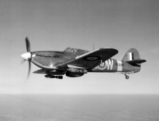A Royal Canadian Air Force Hawker Hurricane Mark IIE (BE485 “AE-W”) of No. 402 Squadron RCAF based at Warmwell, Dorset, in flight carrying two 250-lb GP bombs.