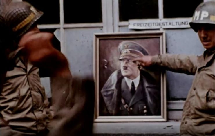 American troops take it in turns to throw darts at a portrait of Nazi leader Adolf Hitler. Public Domain / mediadrumworld.com