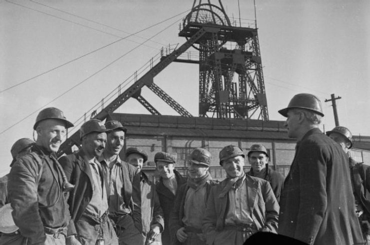 A group of coal miners and ‘Bevin Boys’ talk to a Safety Officer outside the colliery at Ollerton, Nottinghamshire in February 1945.