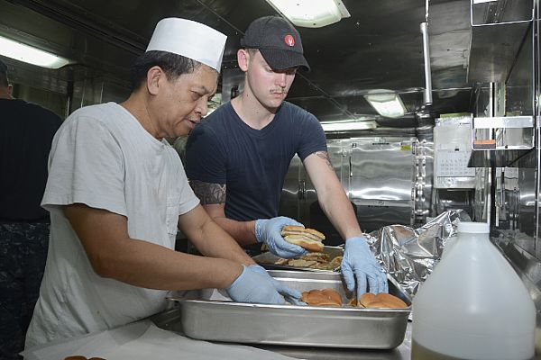 POLARIS POINT, Guam (April 13, 2016) Culinary Specialist Seaman Taylor Dunphy, assigned to the guided-missile submarine USS Ohio (SSGN 726), and 2nd Cook Silverio Mariano, a Military Sealift Command civilian mariner assigned to the submarine tender USS Frank Cable (AS 40), prepare food in Frank Cable’s galley. Ohio Sailors were invited to eat aboard Frank Cable during the submarine’s scheduled maintenance and provided three culinary specialists to work alongside the civilian mariners to prepare meals for the crews. Frank Cable, forward deployed to the island of Guam, conducts maintenance and support of submarines and surface vessels deployed to the U.S. 7th Fleet area of responsibility. (U.S. Navy photo by Mass Communication Specialist 3rd Class Allen Michael McNair/Released)