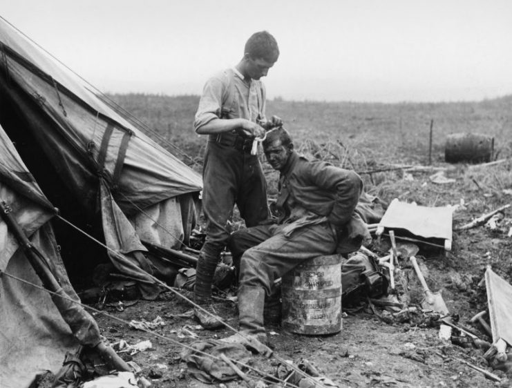 Surrounded by stretchers and bits of bandage, a British medic treats a German soldier’s head wound.