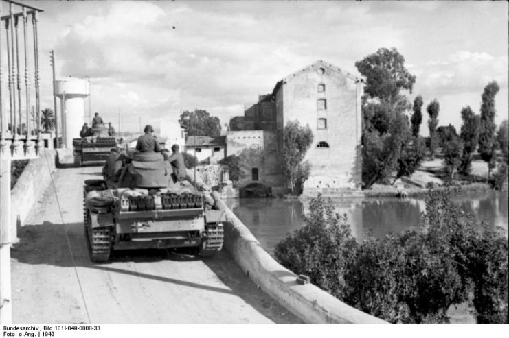 German Panzer Mk III tanks advance through a Tunisian town. By Bundesarchiv – CC BY-SA 3.0 de