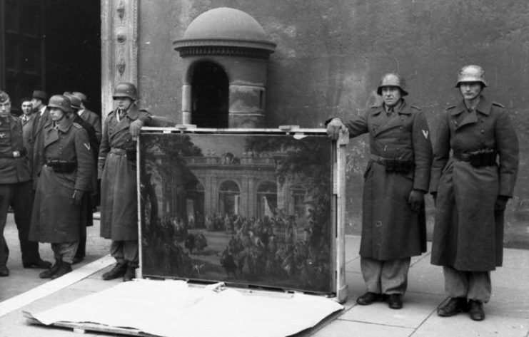 German soldiers of the Hermann Göring Division posing near the main entrance of Palazzo Venezia showing a painting taken from the National Museum of Naples Picture Gallery