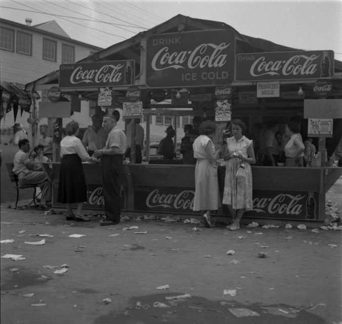 People Gathered By Coca-Cola Stand. Photo: Credit: Rosemary Gilliat Eaton / Library and Archives Canada..