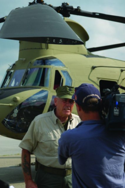R. Lee Ermey stands in front of a CH-47F Chinook helicopter for a segment of his show, “Lock and Load.”