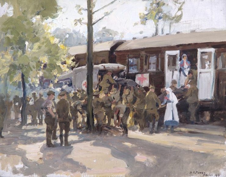 A Red Cross Train, France, 1918. Wounded British soldiers are transferred from a motor ambulance to a Red Cross train, which is on a railway amongst trees.