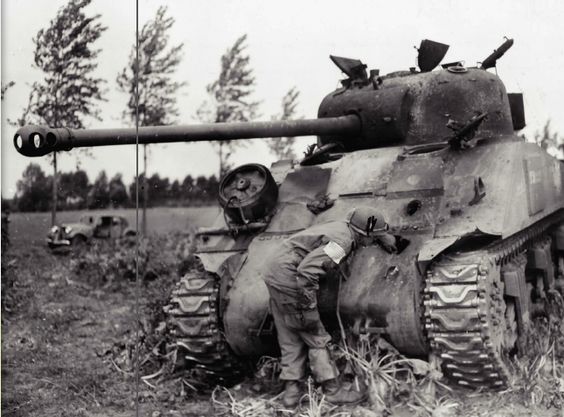 A 101st Airborne trooper studies a knocked-out British Firefly tank along the highway.
