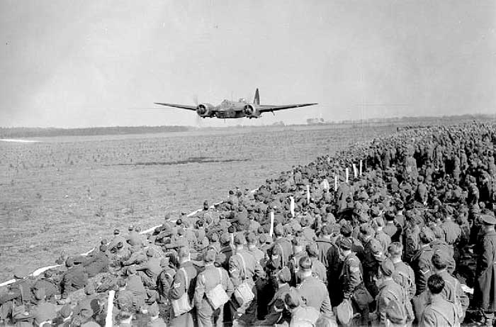 An RAF Blenheim IV light bomber flies low to lay a smokescreen during a demonstration of air power in front of a gathering of Regular and Home Guard officers and NCOs in East Anglia , 29 March 1942.