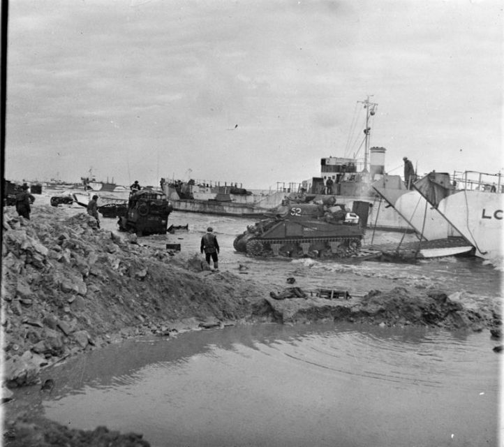 A Sherman tank of ‘A’ Squadron, Nottinghamshire Yeomanry (Sherwood Rangers), 8th Armoured Brigade, comes ashore from a landing craft on Jig beach, Gold area, 6 June 1944.