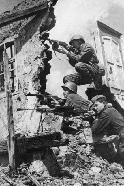 Soviet troops with their automatic weapons in the ruins of a Russian village.