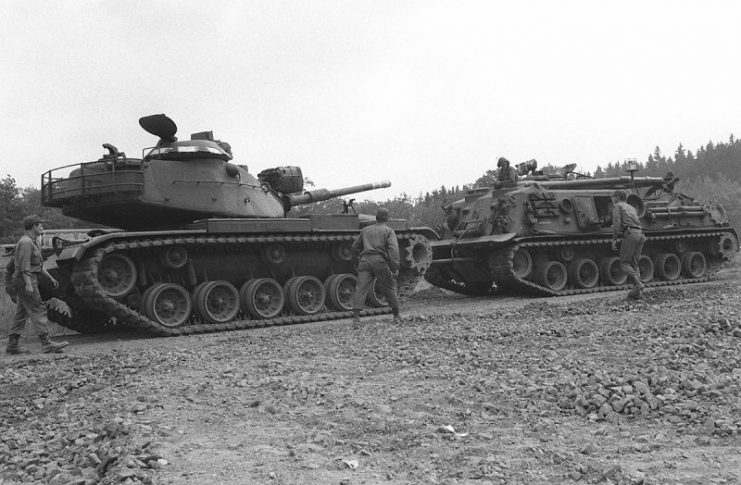 A right front view of an M-88 armored recoery vehicle towing an M-60 main battle tank from a storage shelter in preparation for Exercise REFORGER