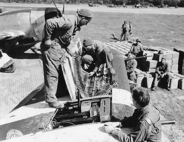 9th Air Force mechanics refill the compartments for the 4 12.7 machine guns on the left side of a Republic P-47 Thunderbolt.