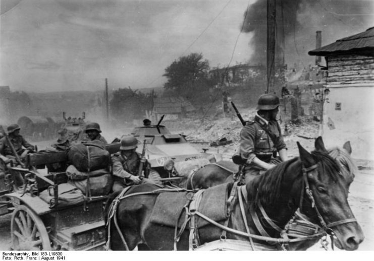 Wehrmacht horse drawn artillery and armored cars of the LSSAH pass a burning Soviet village August 1941. Photo: Bundesarchiv, Bild 183-L19830 / CC-BY-SA 3.0.