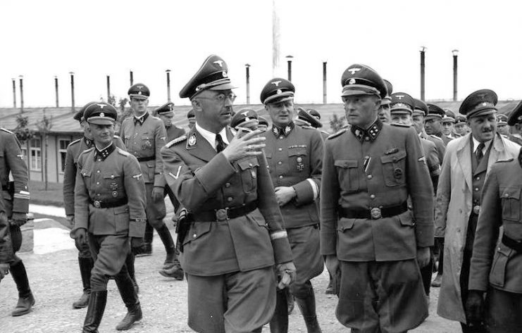 Heinrich Himmler visiting Mauthausen in June 1941. Himmler is talking to Franz Ziereis, camp commandant, with Karl Wolff on the left and August Eigruber on the right. By Bundesarchiv – CC BY-SA 3.0 de