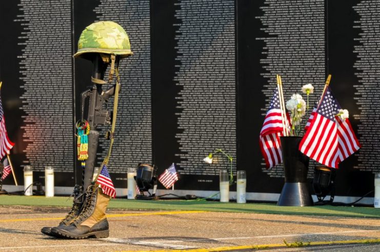 A fallen soldier tribute stands before panels of a replica Vietnam Memorial Wall.