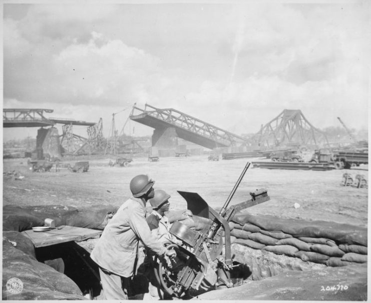 US soldiers guard a newly-constructed bridge site over the Rhine River, built by U.S. Ninth Army Engineers, 1945
