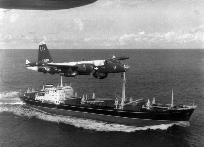 A US Navy P-2H Neptune of VP-18 flying over a Soviet cargo ship with crated Il-28s on deck during the Cuban Crisis.