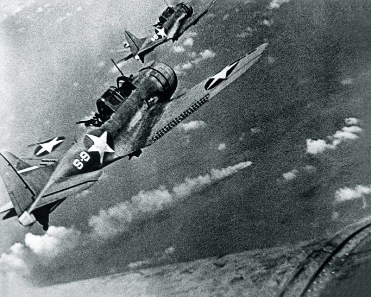 U.S. Navy Douglas SBD-3 “Dauntless” dive bombers from scouting squadron VS-8 from the aircraft carrier USS Hornet (CV-8) approaching the burning Japanese heavy cruiser Mikuma to make the third set of attacks on her, during the Battle of Midway, 6 June 1942.