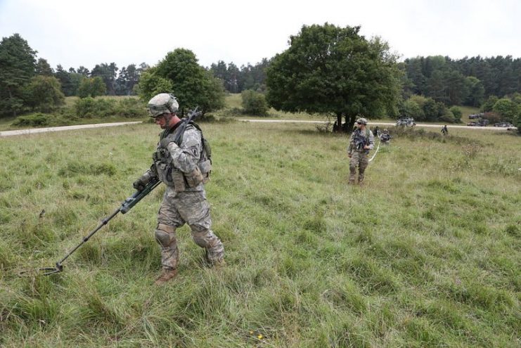 A U.S. Soldier with the 173rd Airborne Brigade Combat Team use a metal detector to safely move through a simulated mine field
