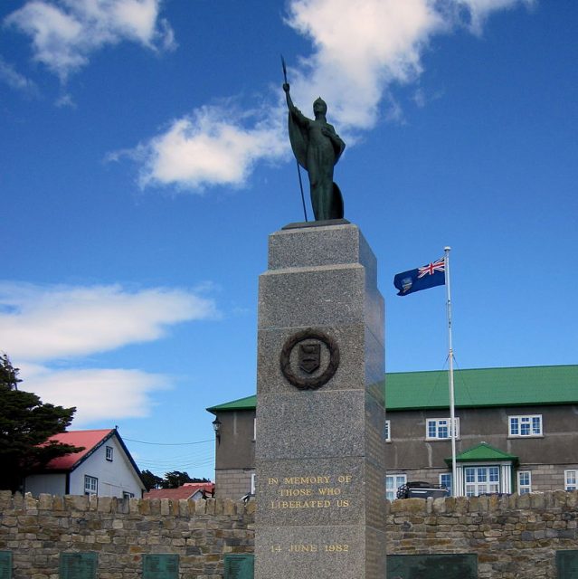 Falklands War Memorial on Ross Road in Stanley, with government buildings on Thatcher Drive in the background.Photo Travellers & Tinkers CC BY-SA 3.0