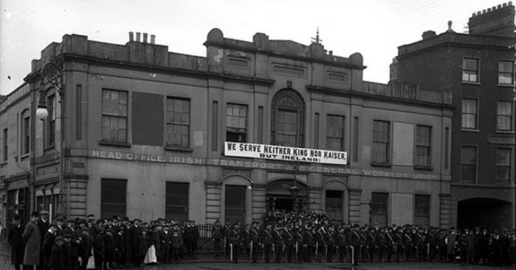 Irish Citizen Army outside Liberty Hall in 1914, in front of a banner reading “We serve neither King nor Kaiser but Ireland”