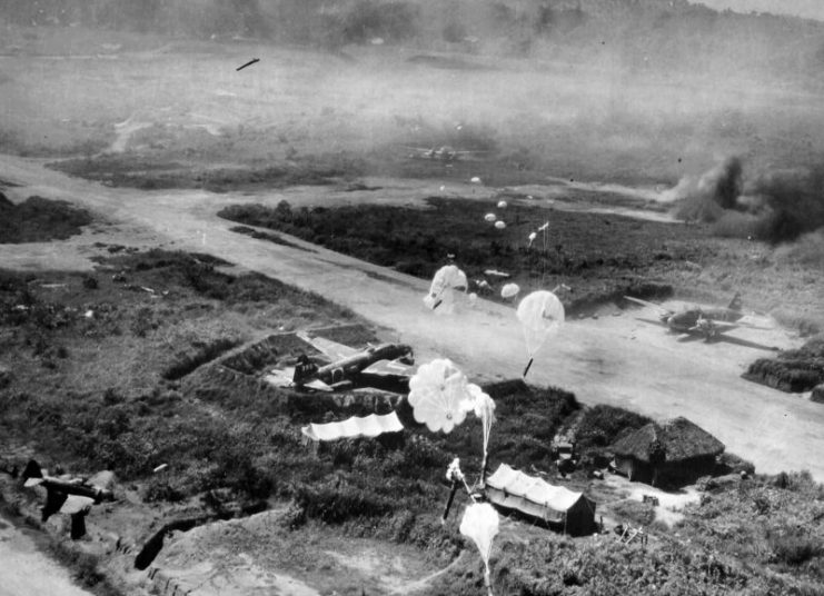 Parachute bombs are dropping from low-flying American planes on revetments protecting dispersed G4M bombers on the runway at Vunakanau Airfield, Rabaul, New Britain