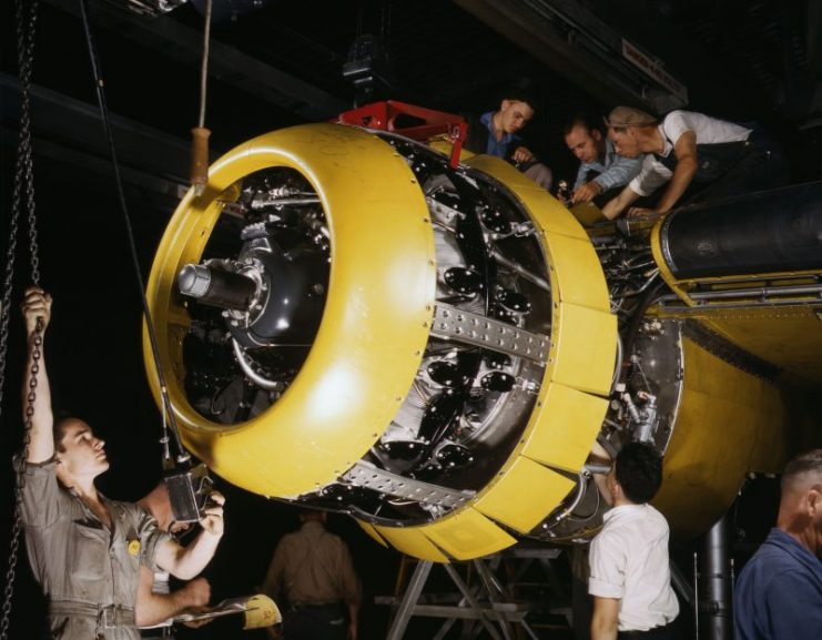North American Aviation factory workers mounting an engine on a B-25 bomber, Inglewood, California, United States, 1942.
