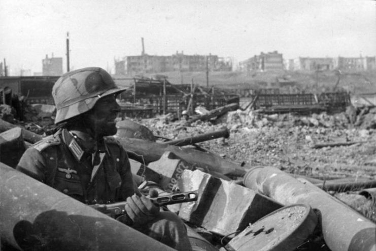 German Soldier with Soviet submachine gun PPSch 41 in cover between rubble. By Bundesarchiv, Bild 116-168-618 / CC-BY-SA 3.0