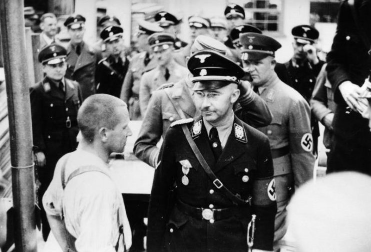 Himmler (front right, beside prisoner) visiting the Dachau Concentration Camp in 1936. By Bundesarchiv Bild  CC-BY-SA 3.0