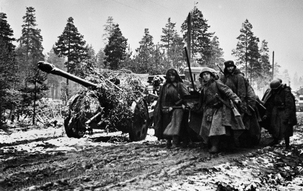 Soldiers pulling camouflaged artillery on muddy roads. The Leningrad Front. By RIA Novosti archive CC BY-SA 3.0