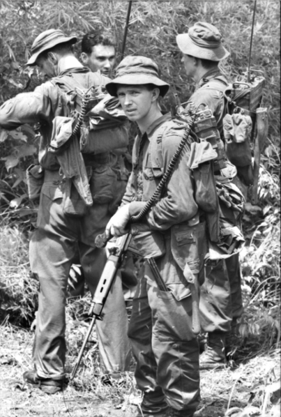 Private Ken Meredith (facing camera) waits with a group of signalers for the order to move back to base after a bitter engagement with the Viet Cong (VC) at Long Tan, in Phuoc Tuy Province. Australians killed 250 VC in this action.