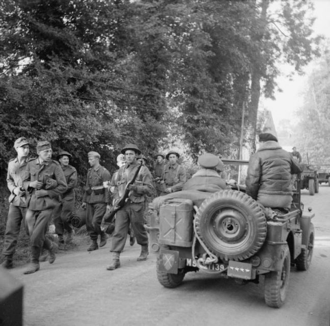 General Montgomery passes German POWs while being driven along a road in a jeep, shortly after arriving in Normandy, 8 June 1944.