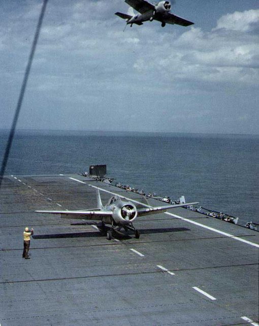 A FM-2 Wildcat fighter prepared to launch from USS Charger while another flew overhead, Chesapeake Bay, Maryland, United States, 8 May 1944