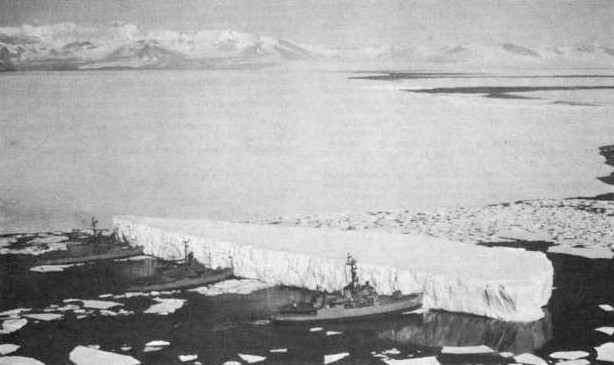 An iceberg being pushed by three Navy ships in McMurdo Sound, Antarctica